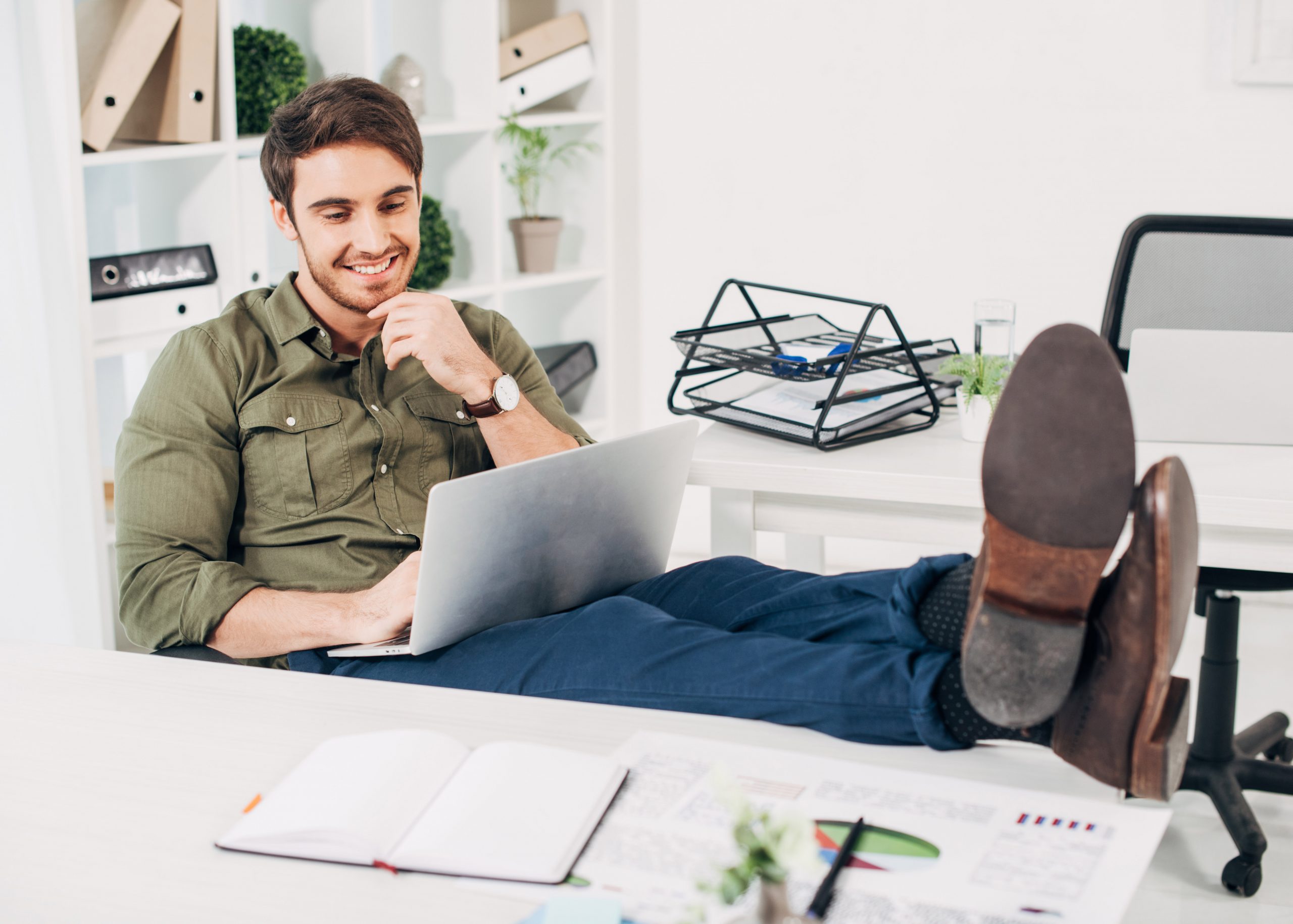 Man with his feet up on his desk looking at laptop. Link takes you to the Bank of Versailles Regular Checking page.