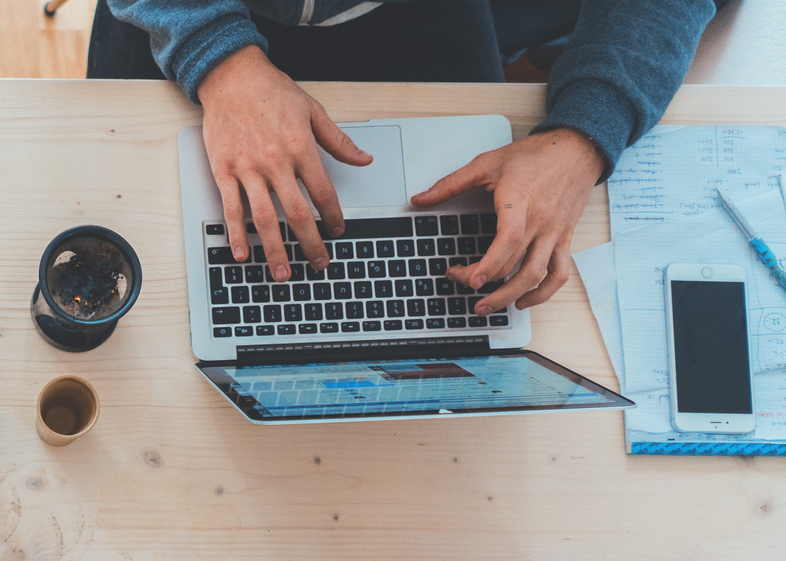 Person working on computer at wooden table.