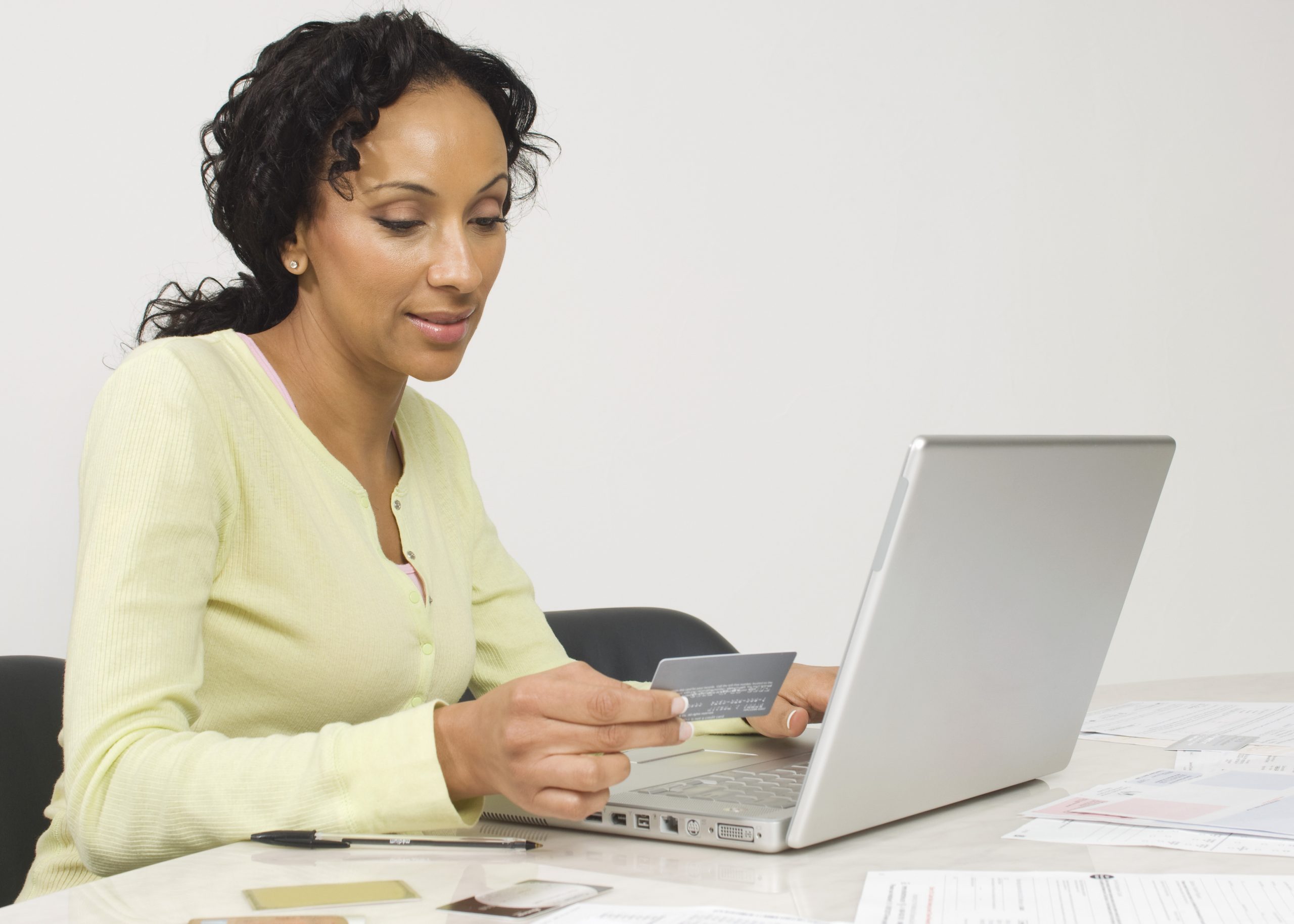 Adult woman using laptop and debit card. Link takes you to the Bank of Versailles Tiered Checking page.